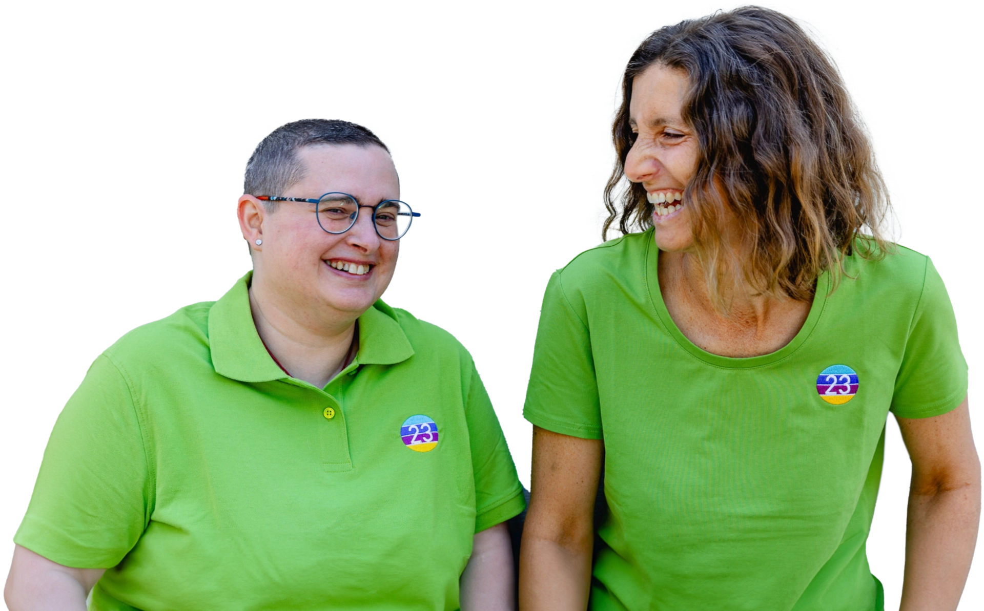 Zwei Frauen in grünen T-Shirts, die lachen und nebeneinander stehen, mit Aufklebern auf ihren Oberteilen.